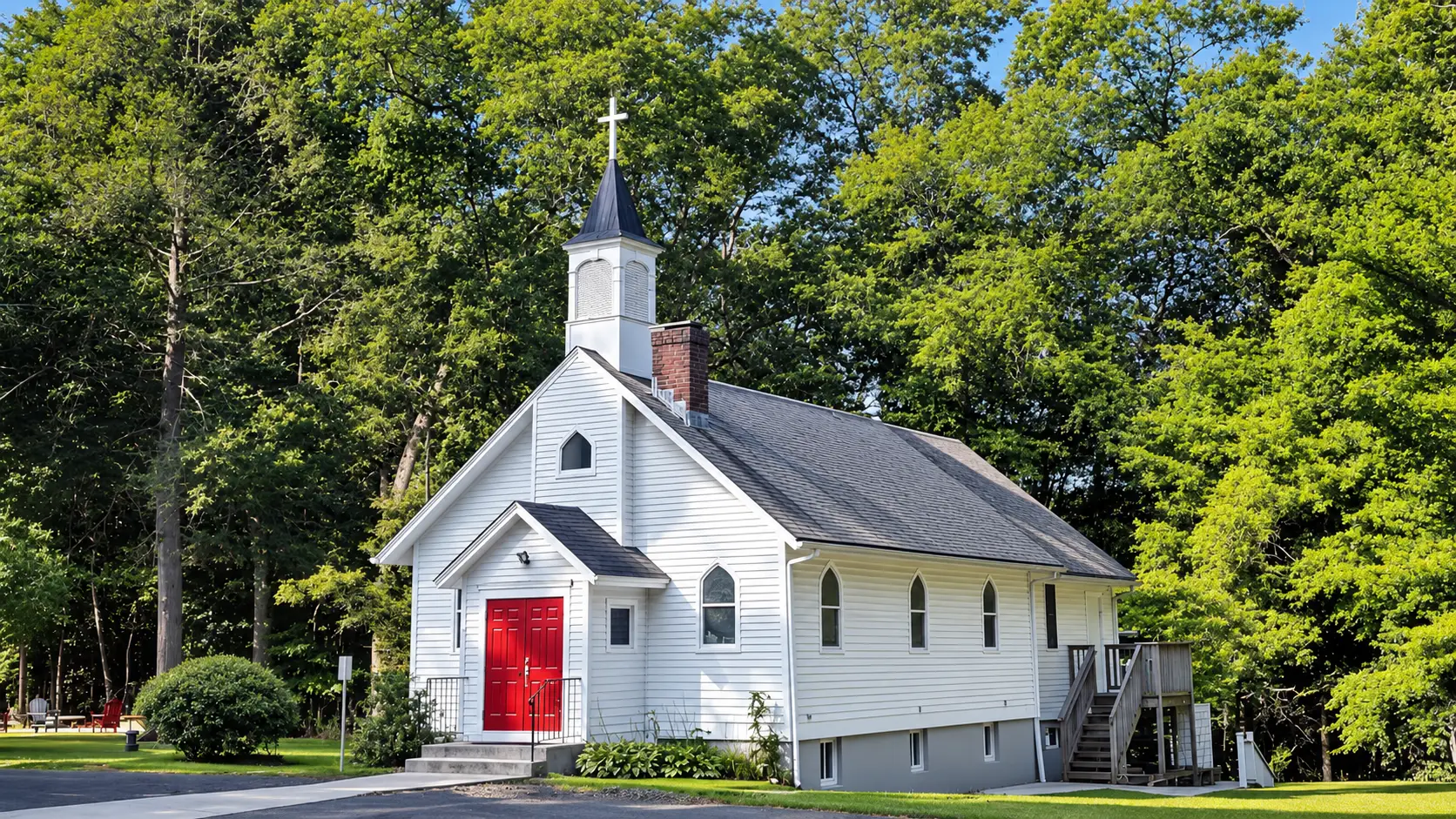 Riverside Community Church, a white clapboard church with a red door and a steeple, under summer trees